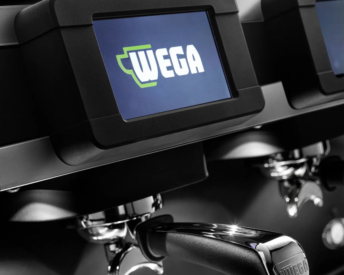 Close-up of a WEGA commercial espresso machine with a digital display screen, metal portafilter, and bright green WEGA CONCEPT branding on a dark metallic surface. Buy online in Ireland at Fzin Coffee