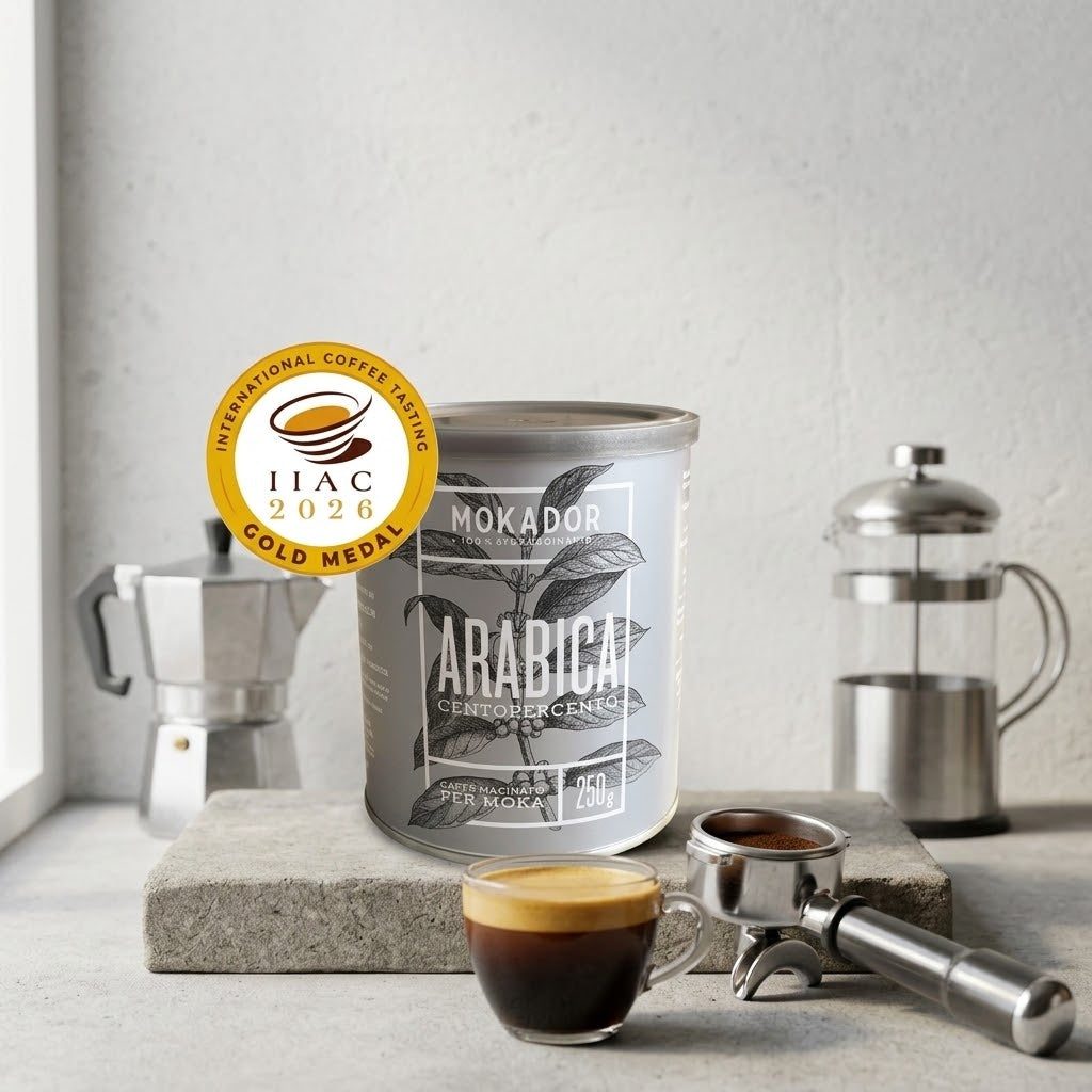 A tin of Mokador Arabica Ground Coffee, with a cup of espresso, a portafilter, a moka pot, and a French press around it. A gold IIAC 2026 Gold Medal badge is overlaid on the left side. Fzin Coffee Ireland