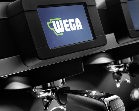 Close-up of a WEGA commercial espresso machine with a digital display screen, metal portafilter, and bright green WEGA CONCEPT branding on a dark metallic surface.